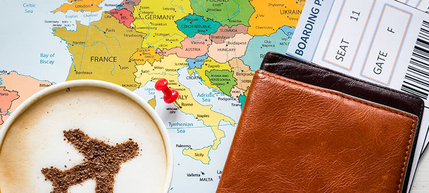 Reiseunterlagen auf einer Landkarte mit Kaffee